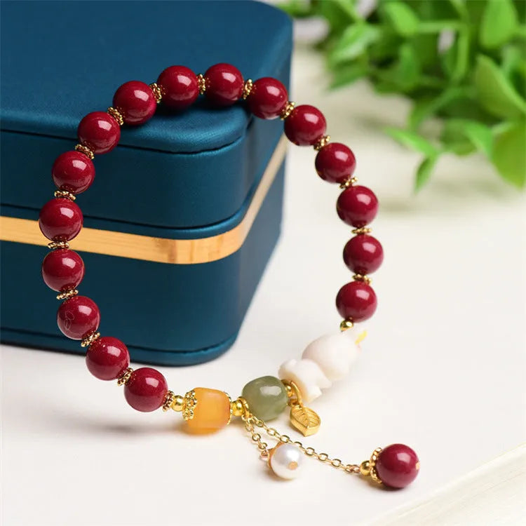 Natural cinnabar bracelet with hand-carved rabbit charm and metallic accents in deep purple-red colour