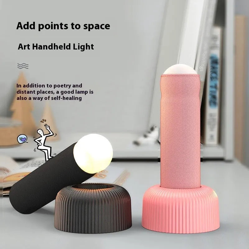 Creative handheld night light with fabric covering on base, emitting warm light