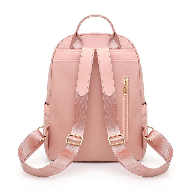 Women's black casual nylon backpack with double straps and a front pocket, shown next to a pink version.