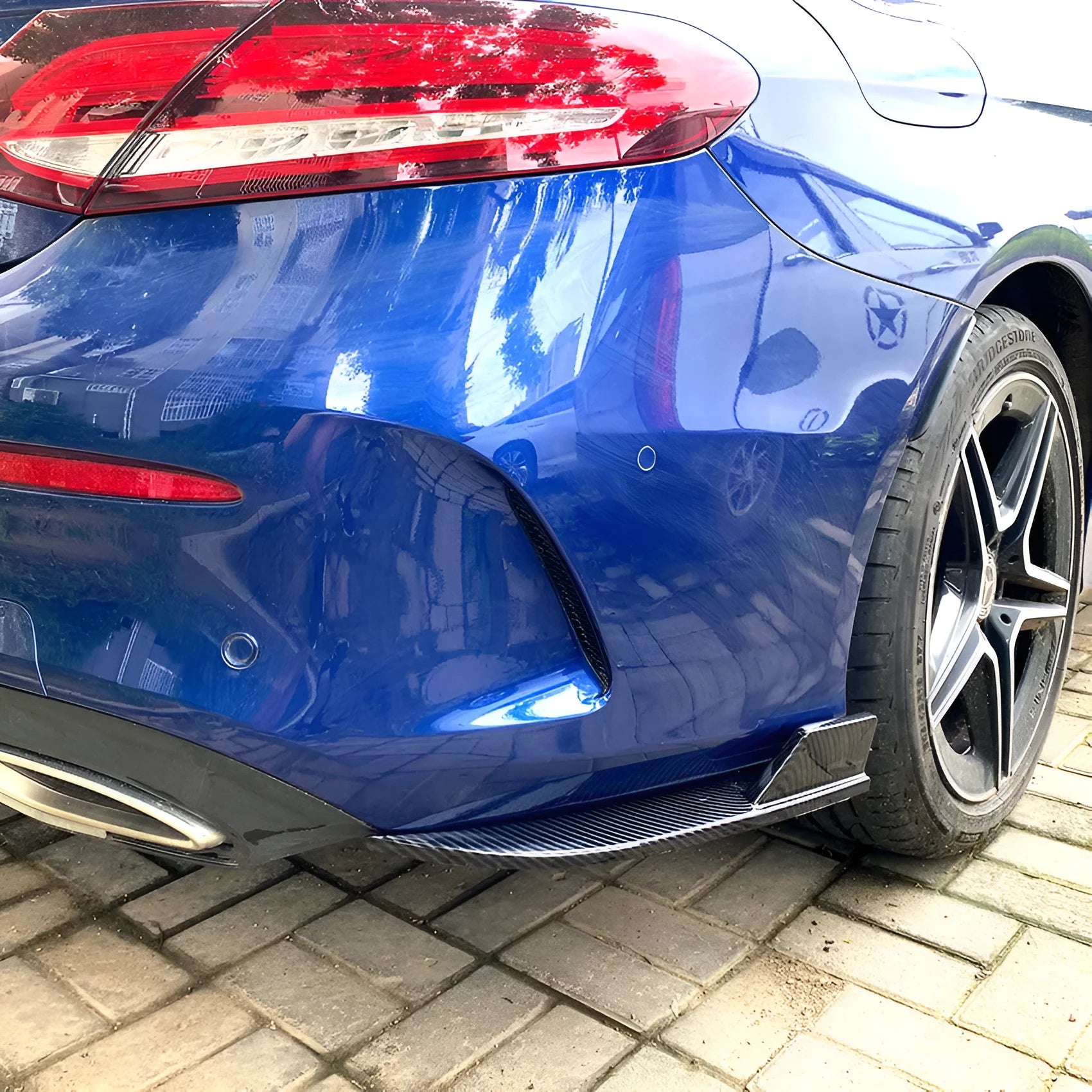 Pair of car rear bumper corner protectors in carbon fibre pattern on a vehicle rear corner