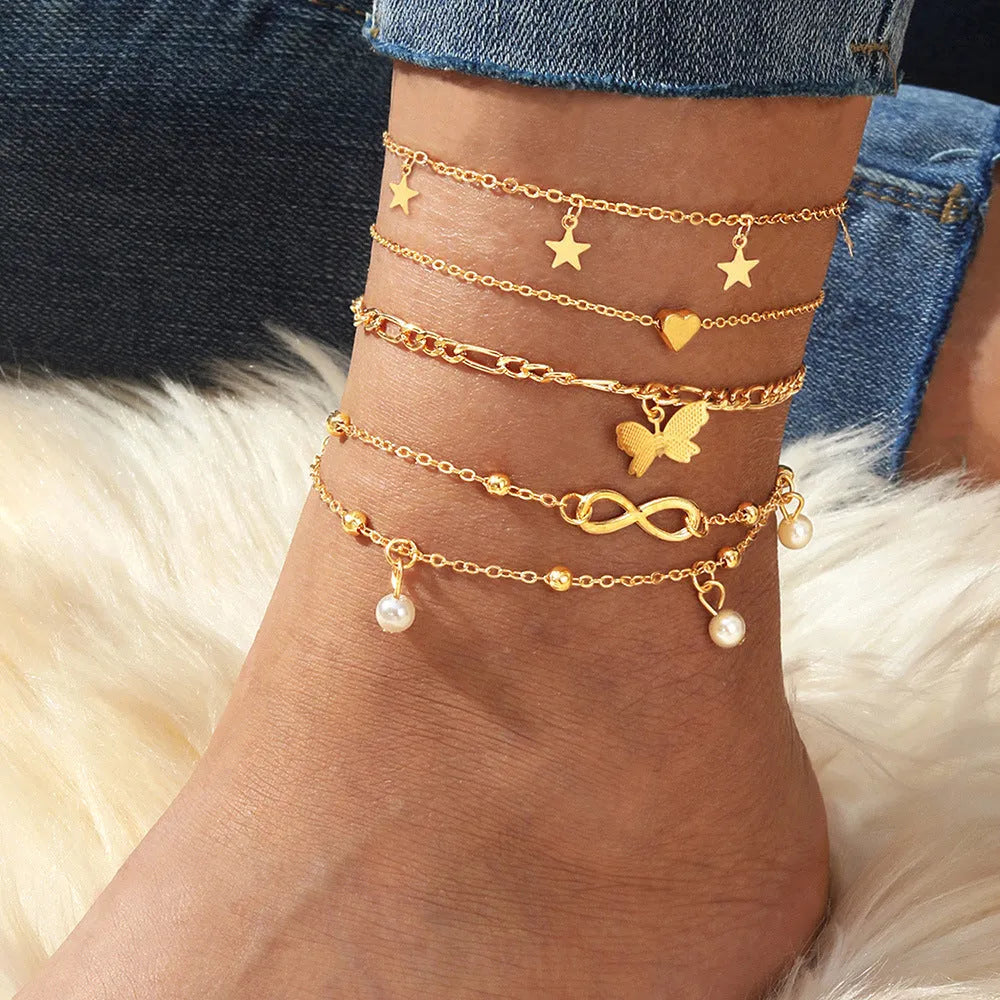 Set of four women's alloy anklets with butterfly, pearl, and heart charms.