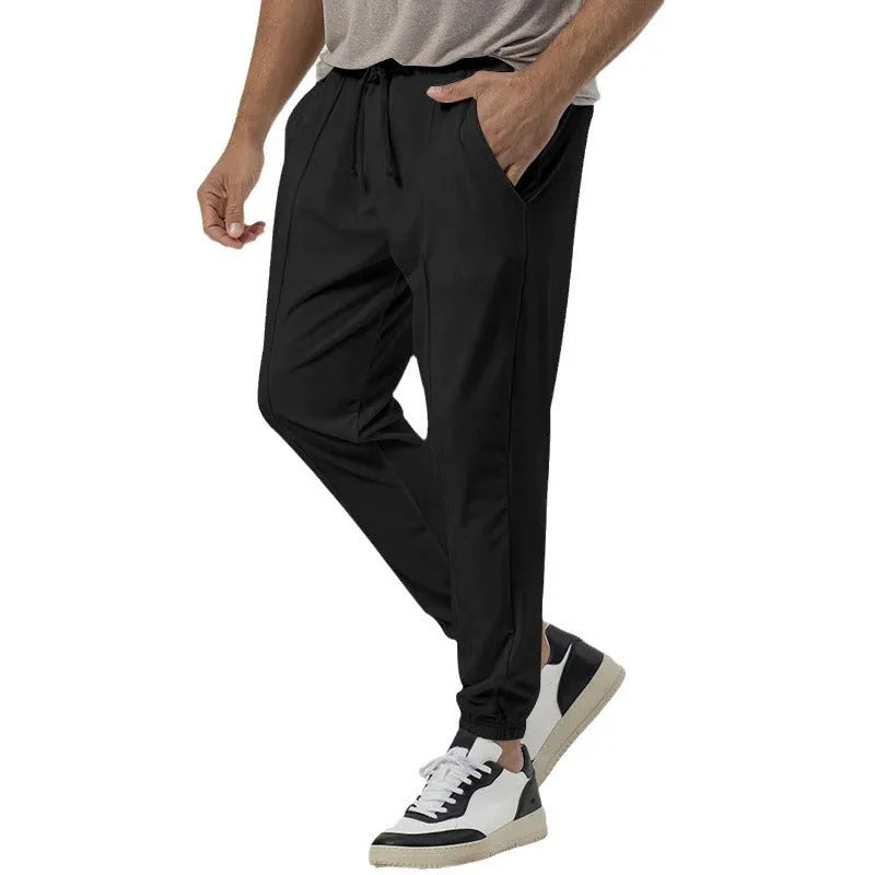 Man wearing grey loose tapered track sweatpants with a straight-leg design and elasticated waist.