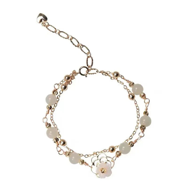 Yellow gold electroplated copper women's bracelet with geometric design showing butterfly and shell flower charms including Hetian jade elements