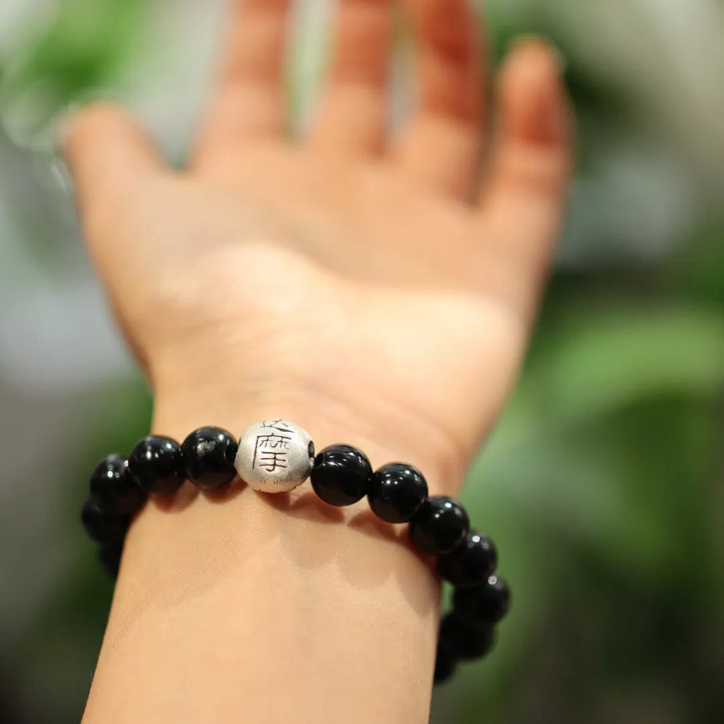 Close-up of a black agate beaded bracelet with a sterling silver clasp on a wrist.