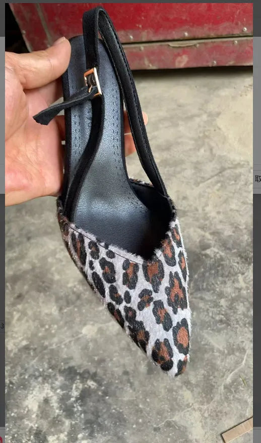 Women's leopard print suede sandals with a pointed toe and high heel on a plain background.