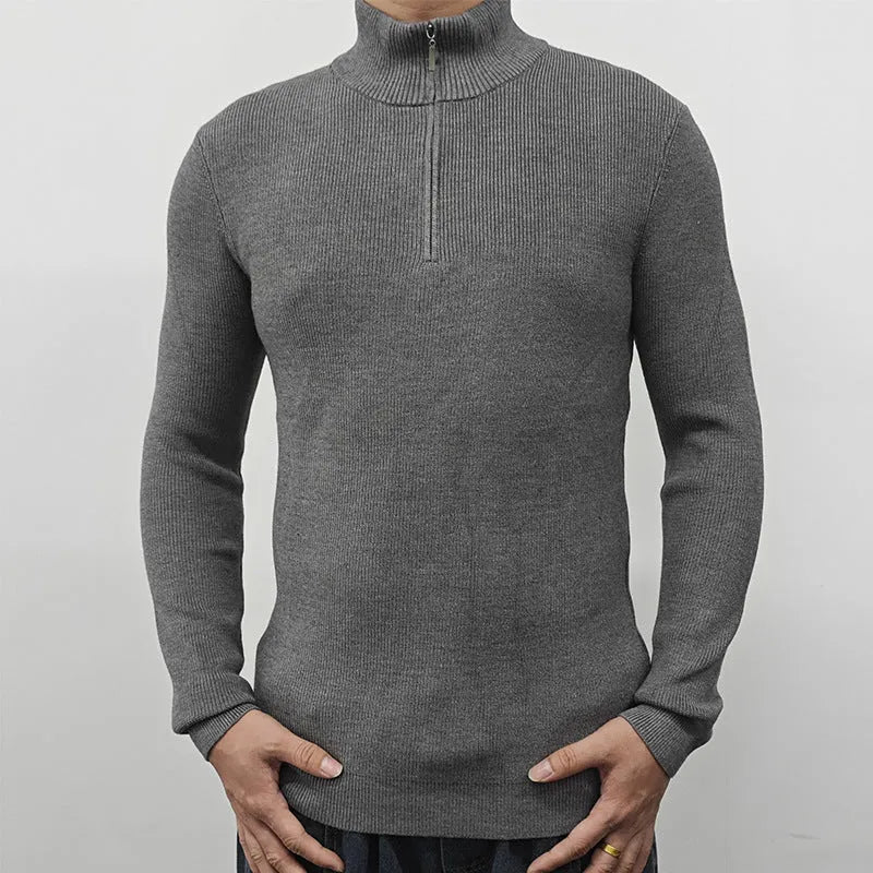Man wearing a grey half-turtleneck zip-up sweater, showing the front zipper and long sleeves.