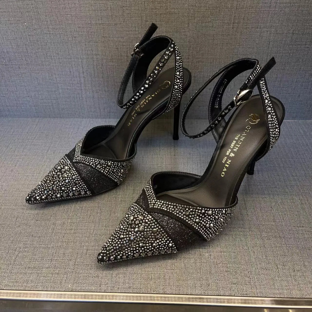 Women's black hollow high heels with red sole and stiletto heel on a plain background.