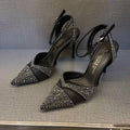 Women's black hollow high heels with red sole and stiletto heel on a plain background.