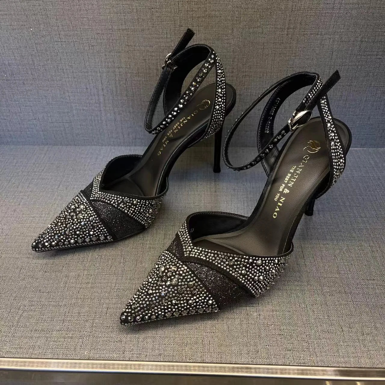 Women's black hollow high heels with red sole and stiletto heel on a plain background.