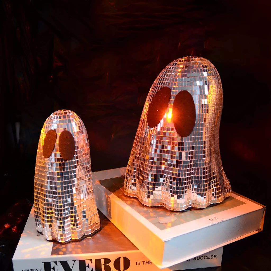 Silver glass ghost decoration with mosaic mirror patch on a desktop for Halloween.
