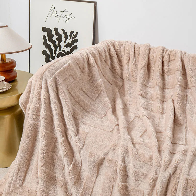 A square thick coral fleece blanket in a solid colour or floral pattern, shown draped over a sofa.