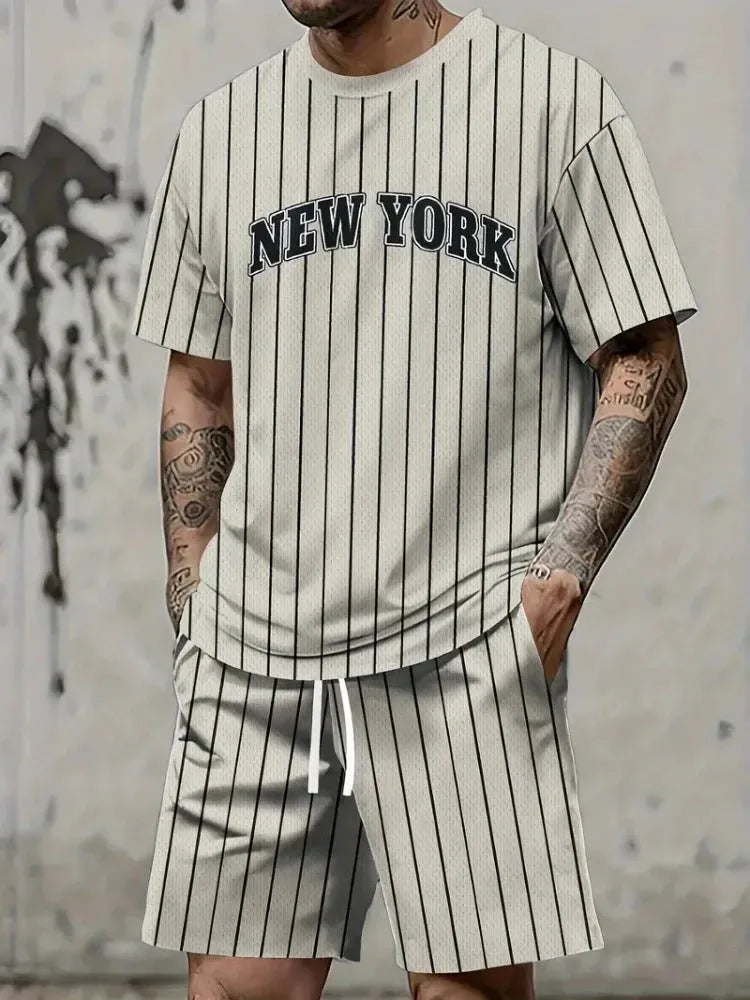 Man wearing a grey 3D printed letter short sleeve top and matching shorts from a sports co-ord set.