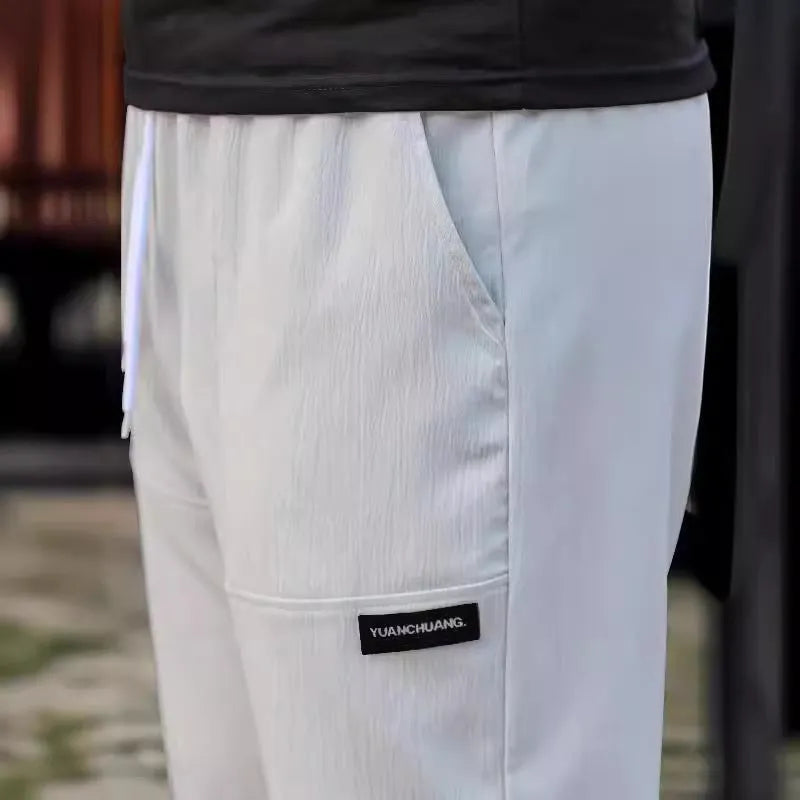 Men's light grey polyester trousers for spring and autumn seasons laid flat.