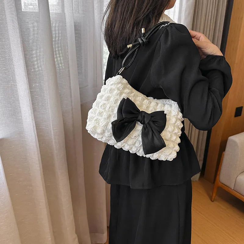 Women's black canvas one-shoulder handbag with a single strap and external sandwich pocket.