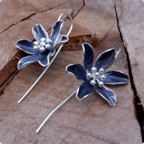 Close-up of a pair of purple flower-shaped alloy stud earrings with an electroplated finish.