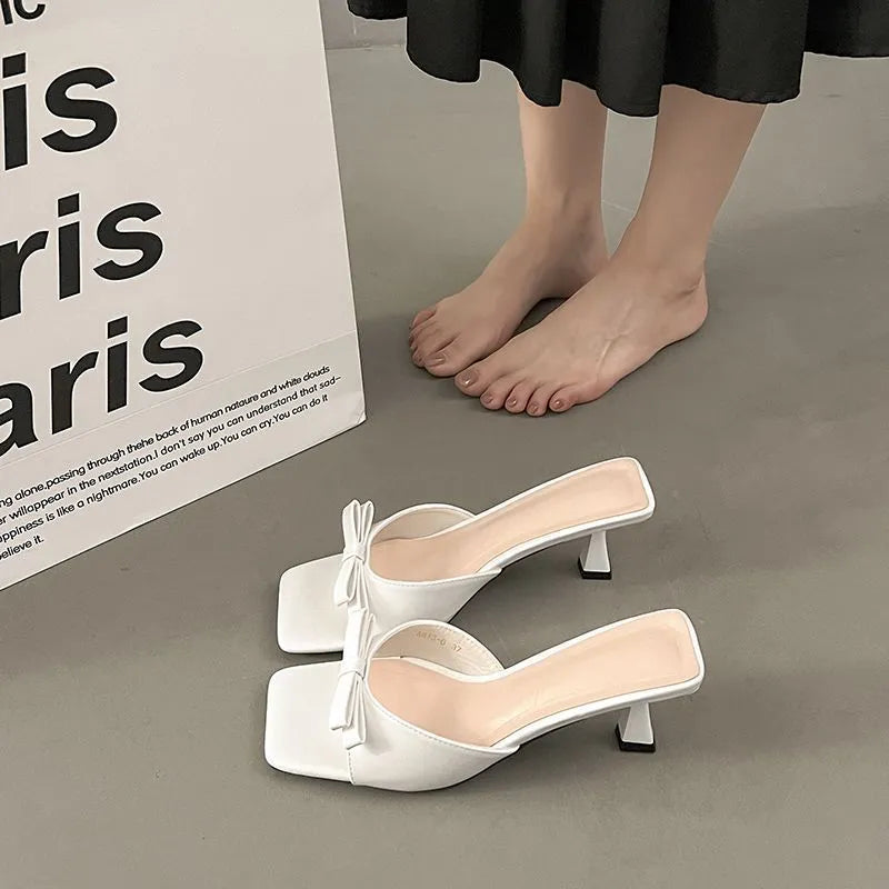 Bow slippers with PU upper and rubber sole in black, white, or pink, sizes 34 to 40