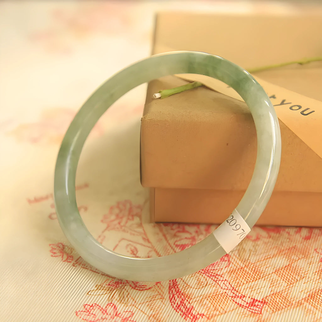 Green handmade geometric jade waxy bracelet with adjustable sizing on a wrist.