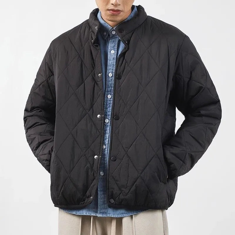 Man wearing a black diamond lattice quilted long-line winter jacket with a loose fit.