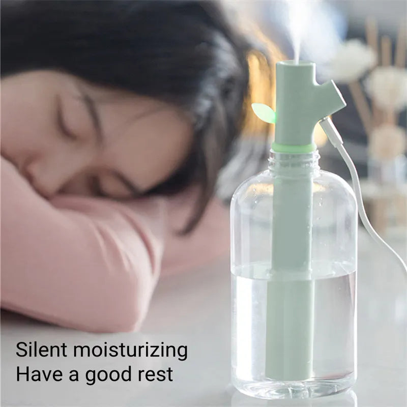 Transparent plastic USB-powered bottle humidifier with a decorative wooden branch diffuser.