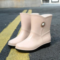 Women's middle tube PVC rain boots in beige, black, and purple with a non-slip sole.
