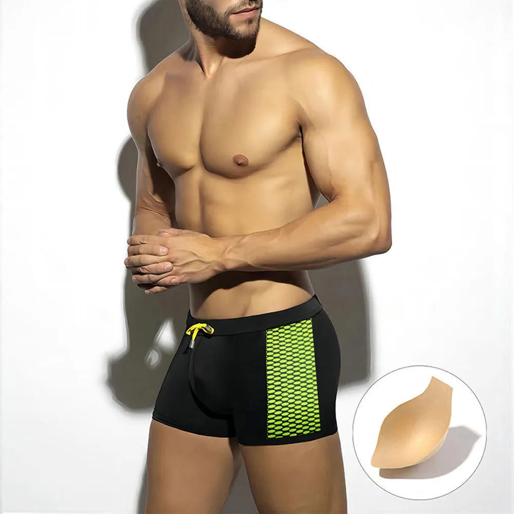 Men's yellow polka dot print swimming boxers with a black ribbon detail on a mannequin.