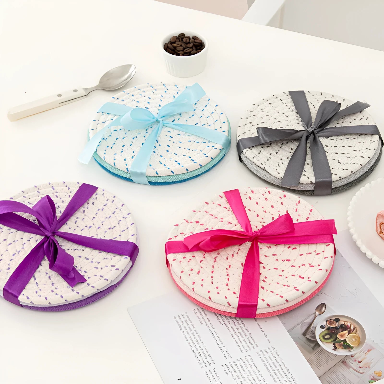 Three round cotton cord coasters in coordinating colours on wooden table
