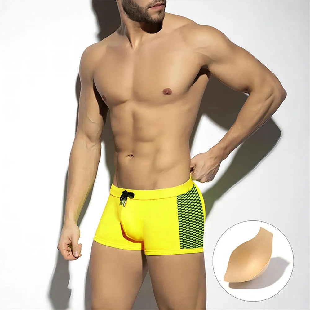 Men's yellow polka dot print swimming boxers with a black ribbon detail on a mannequin.