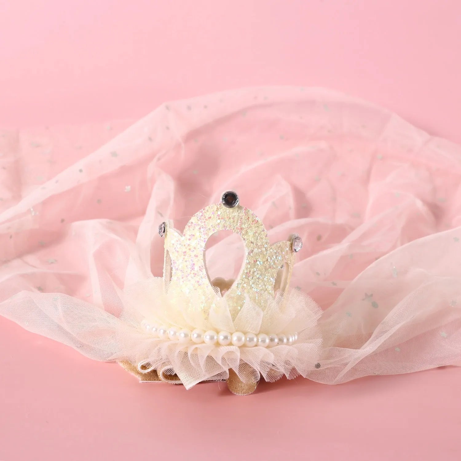 Beige and pink princess crown headdress with veil for cats on a plain background.