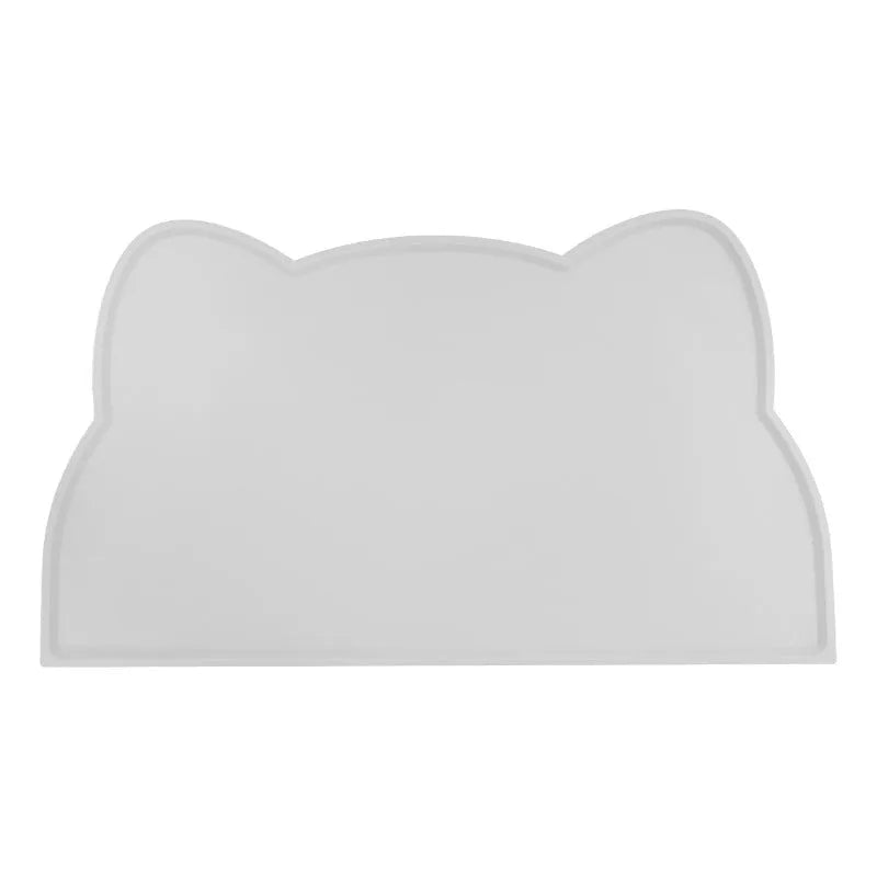 Blue silicone cat head shaped pet feeding mat placed on a wooden floor.