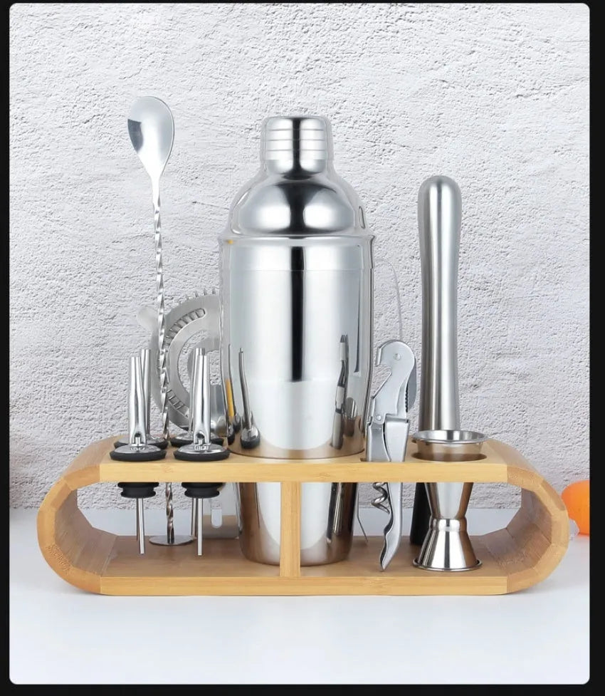 23-piece stainless steel and acrylic cocktail set with shaker, bar spoons, and strainers on a wooden bar.
