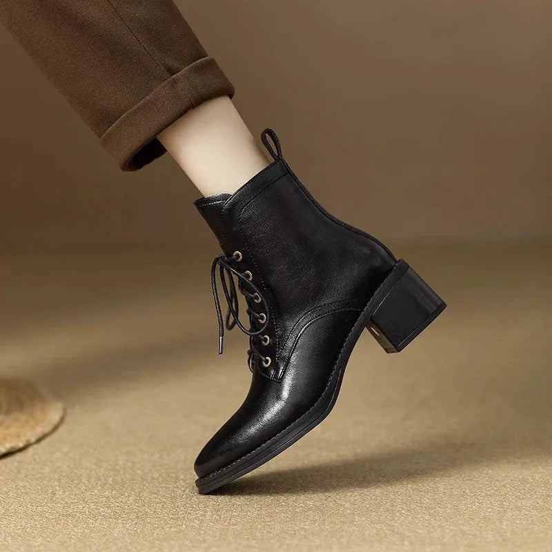 Women's black pointed-toe ankle boots with a low heel on a plain background.