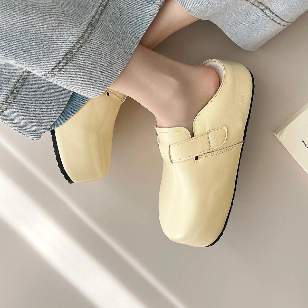 Flat buckle casual sneakers in yellow, creamy-white, silver, and black colours showing round toe and buckle detail.