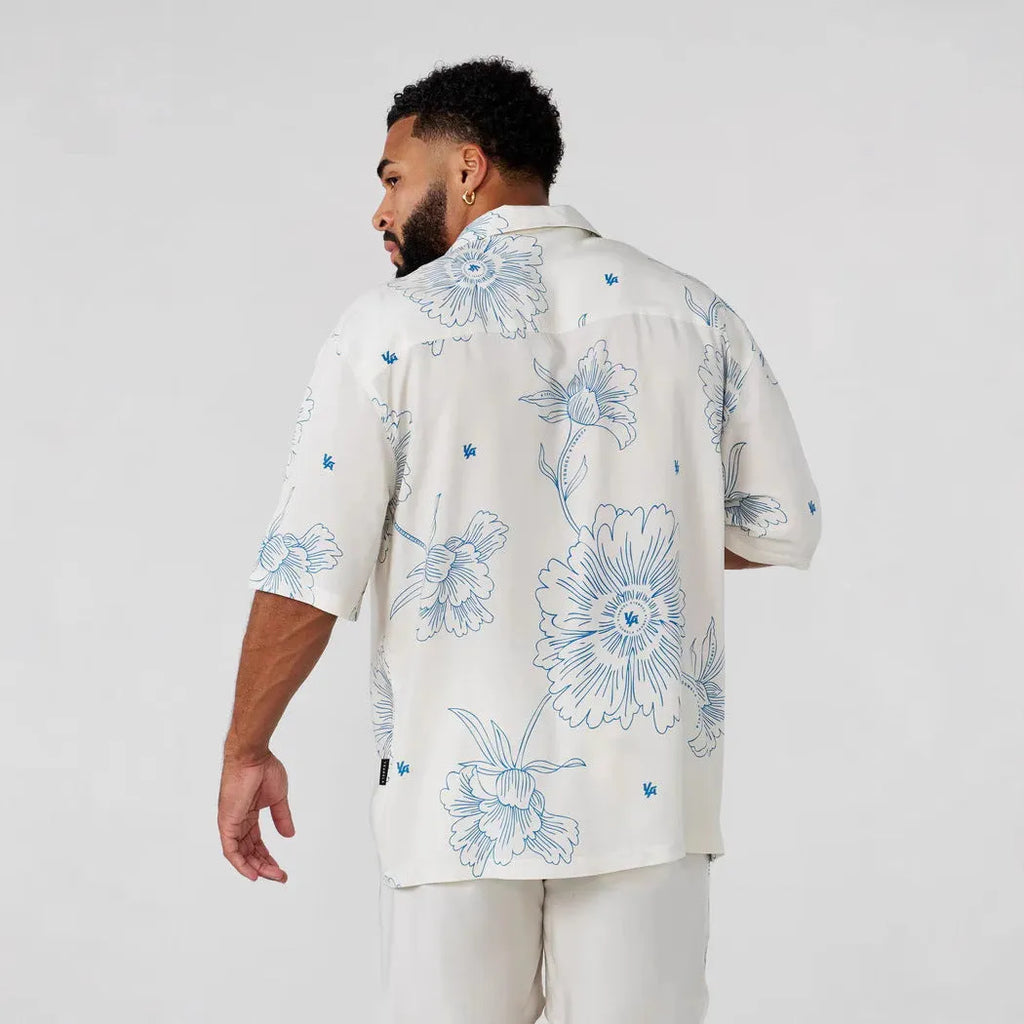 Man wearing a loose-fit, short-sleeve floral print cardigan in a light colour.
