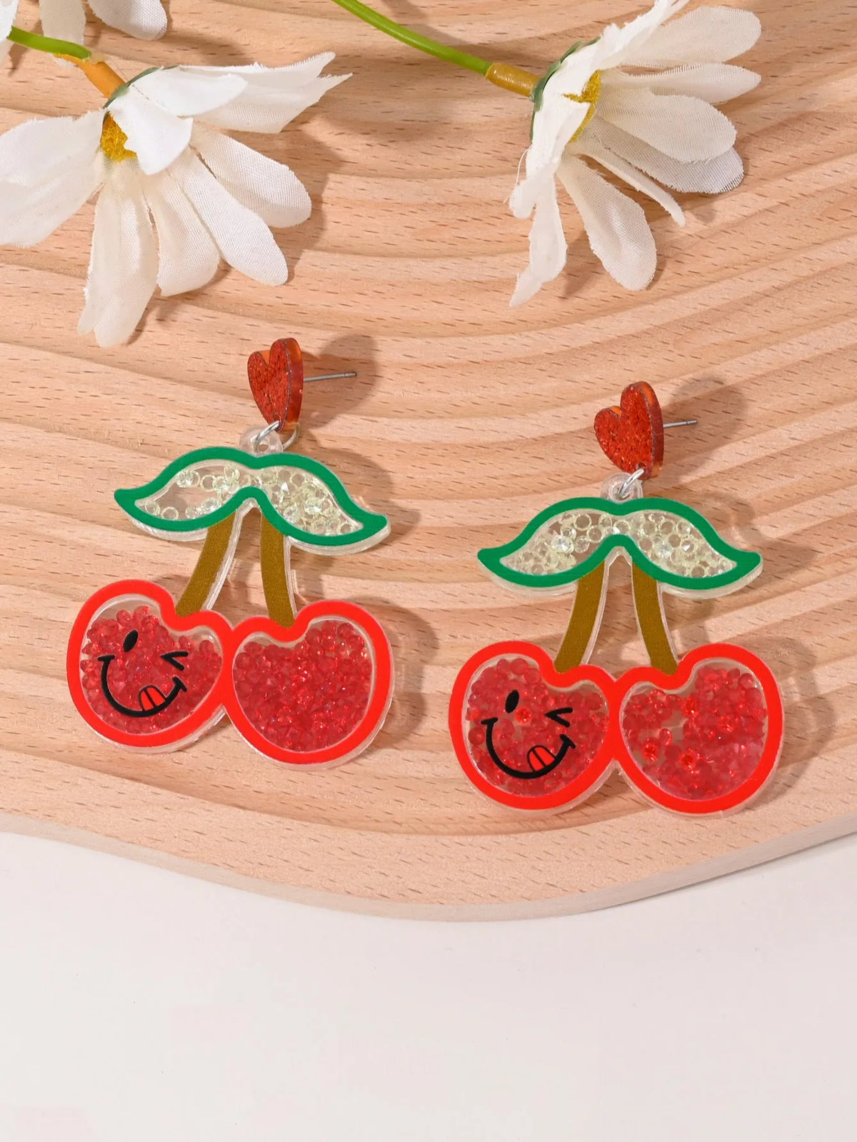 Acrylic drop earrings shaped like a strawberry, cherry, watermelon, pineapple, cake, ice cream, and coconut tree on a white background.