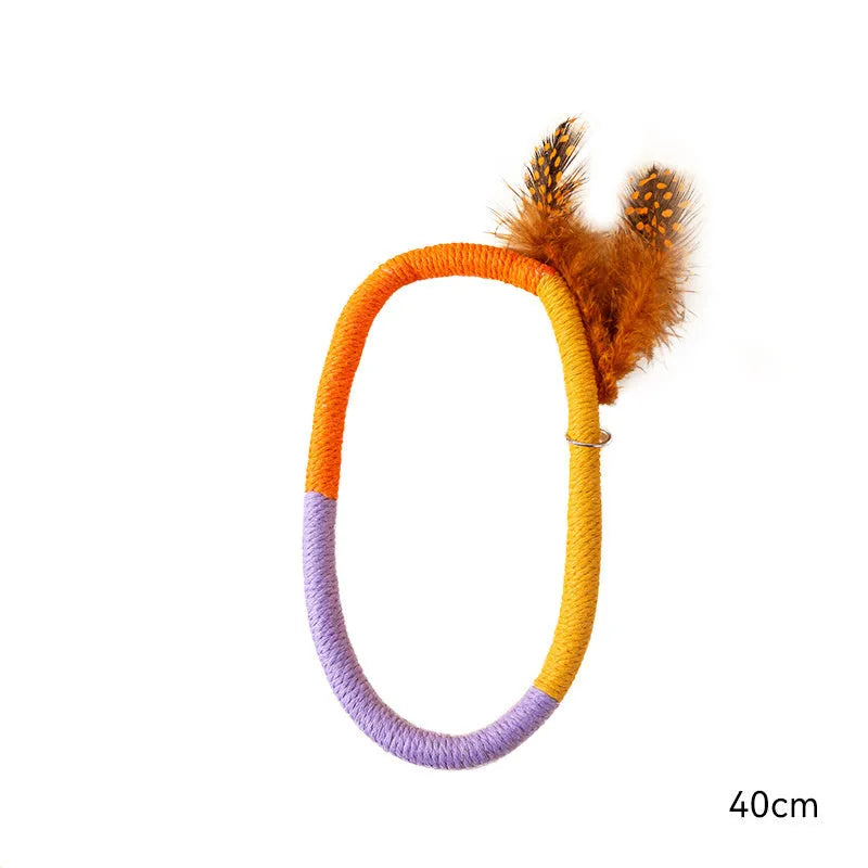 Circular green cotton rope cat toy with white feathers attached on a wooden floor.