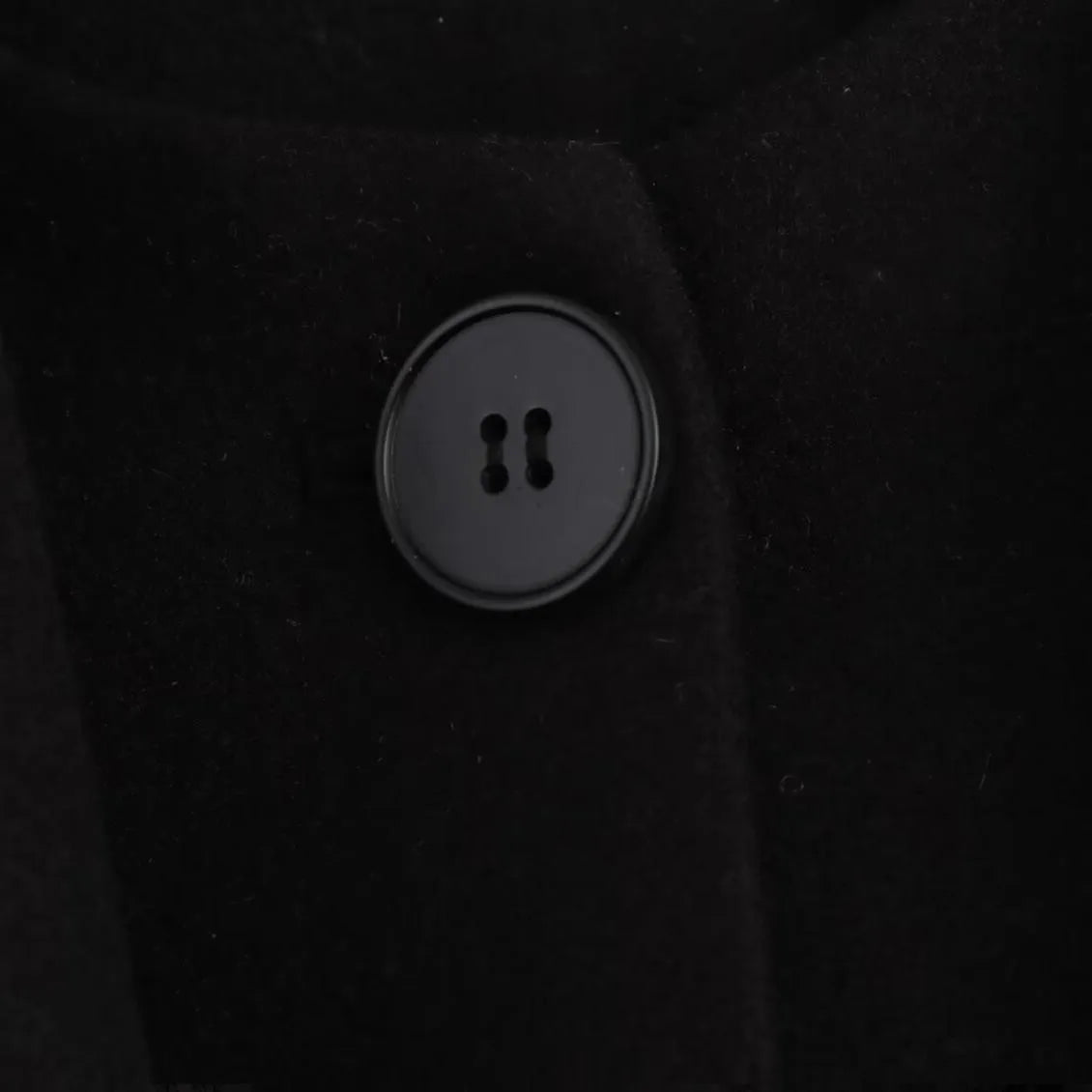 Women's long black coat with a grey artificial fur collar and front pockets.