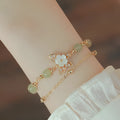 Yellow gold electroplated copper women's bracelet with geometric design showing butterfly and shell flower charms including Hetian jade elements
