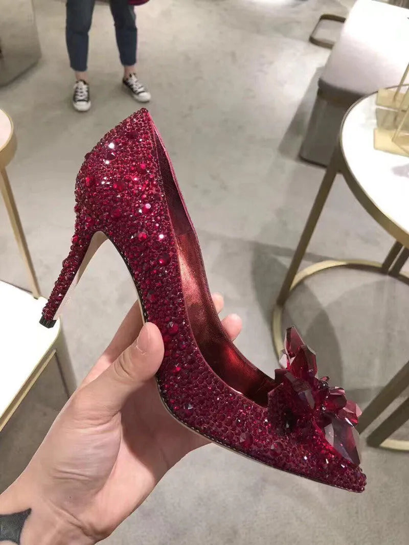 Gold women's pointed toe high heels with rhinestone and bow decoration on a stiletto heel.