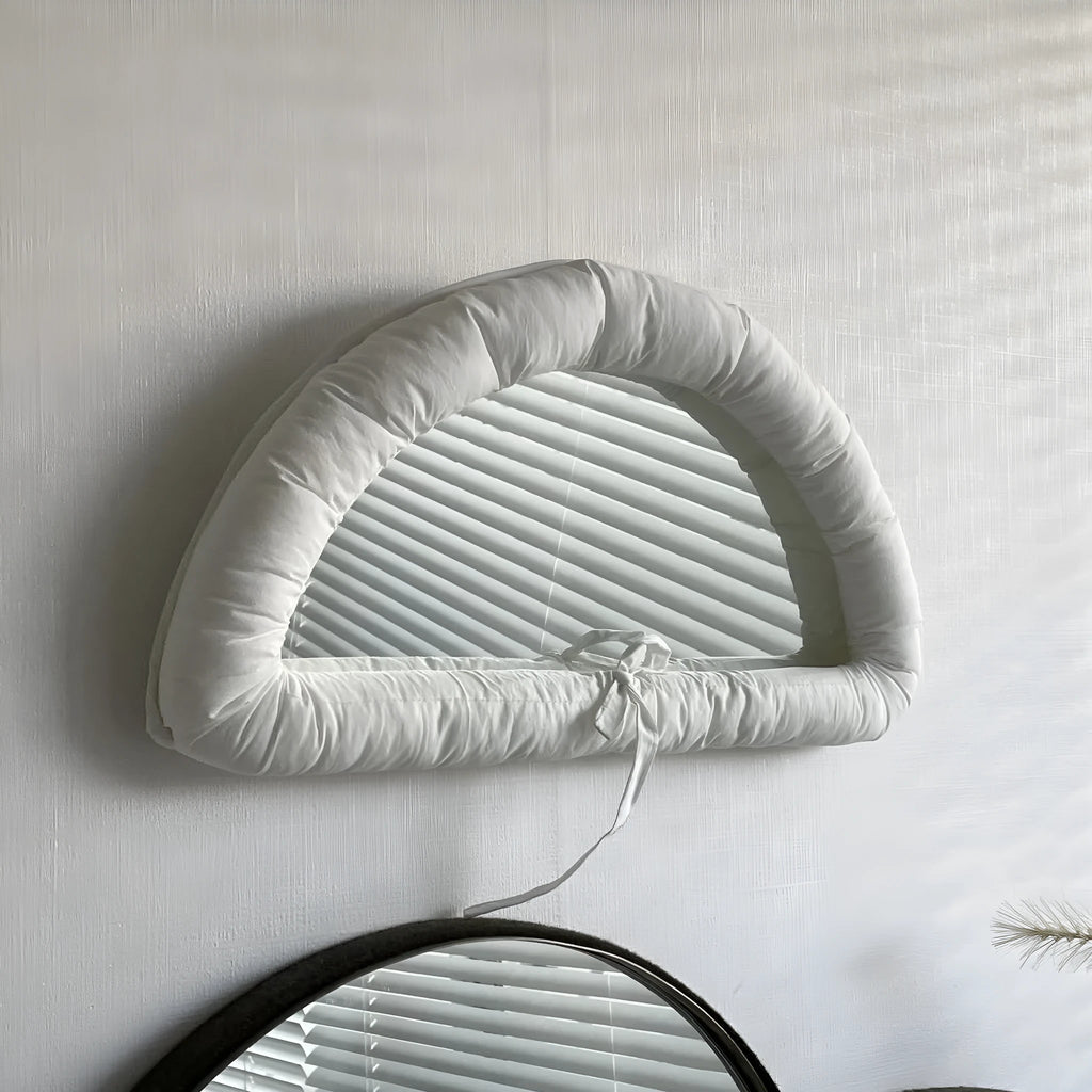 White cotton-filled PVC fabric mirror hanging on wall measuring 23x40x5cm