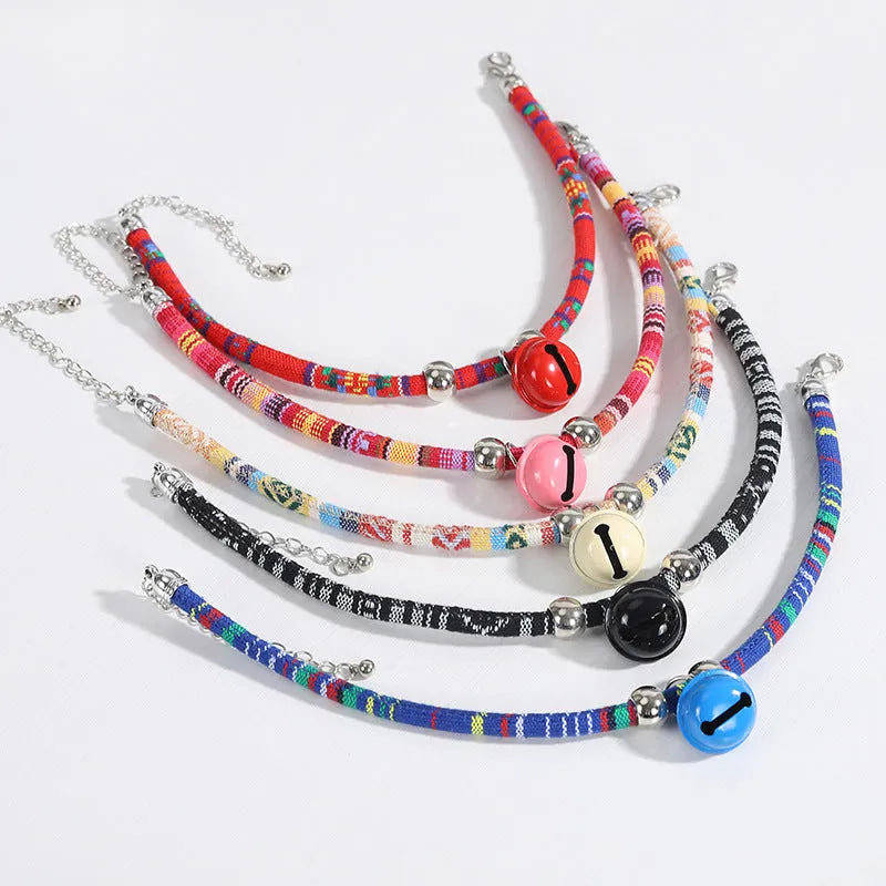 Coloured adjustable nylon pet collar with a metal buckle and brass bell in black, blue, pink, red, and white options.