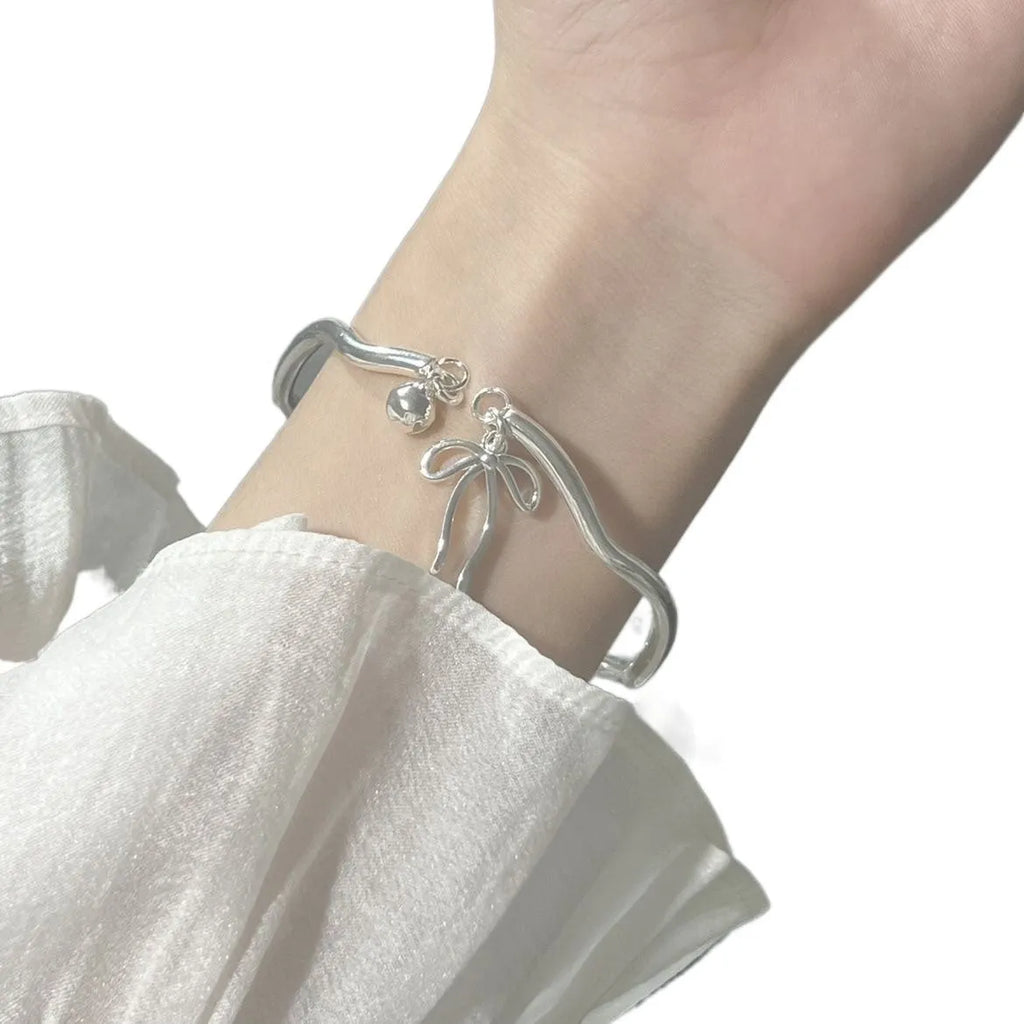 Silver adjustable bracelet with bow charm and opening bell clasp