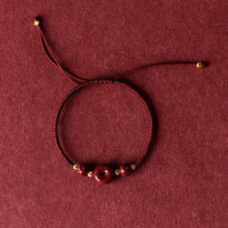 Heart-shaped cinnabar safety buckle bracelet on an adjustable rope cord.