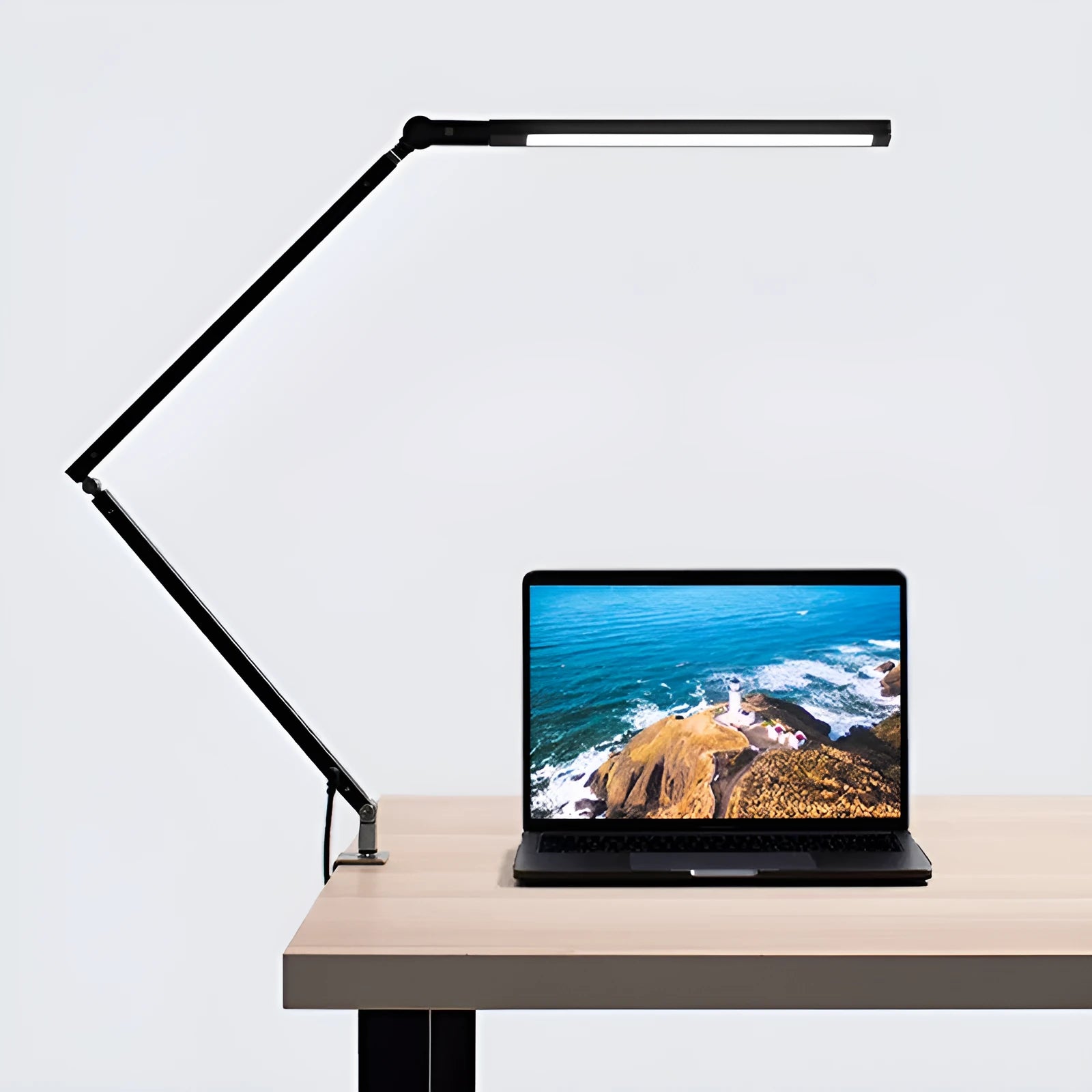 Clip-on aluminium desk lamp with remote control in dazzling black colour, mounted on a desk edge.