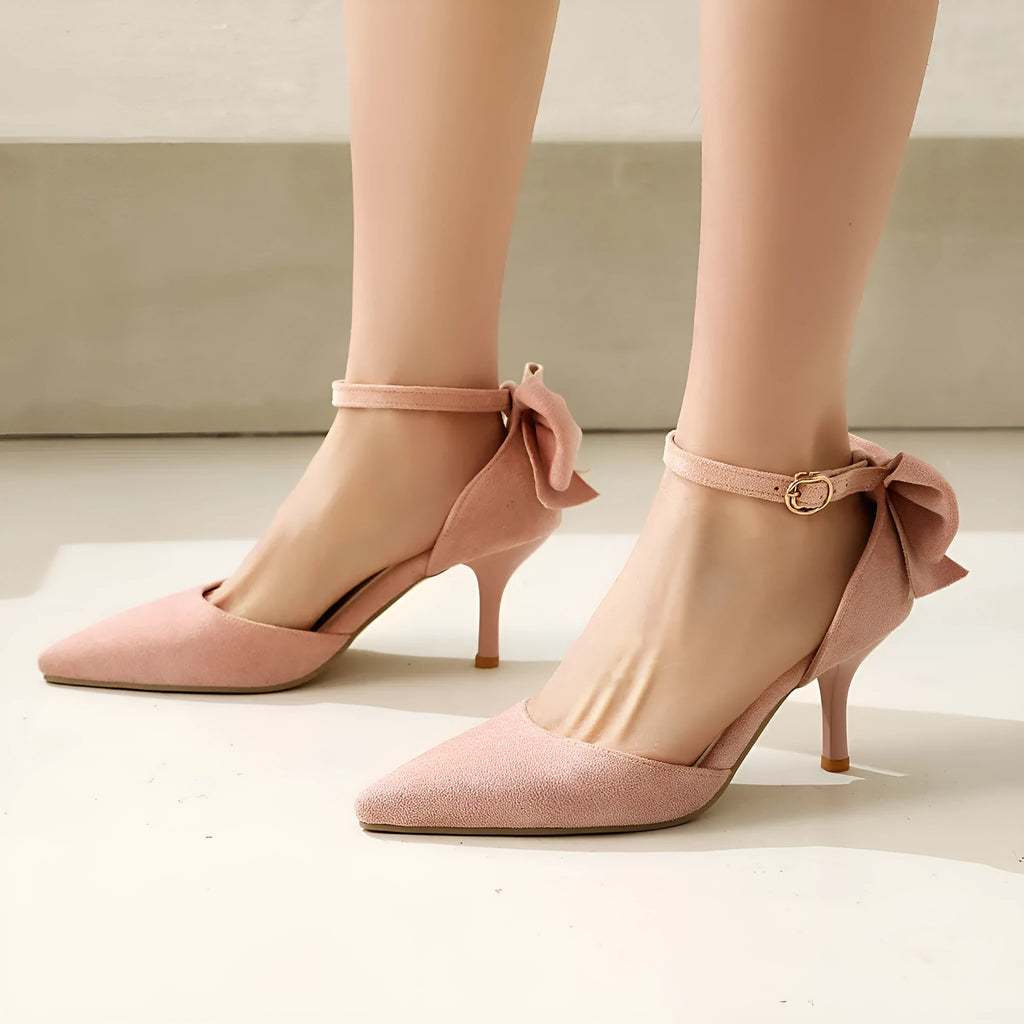 Beige suede pointed-toe stiletto heels with a decorative bowknot and buckle fastening.