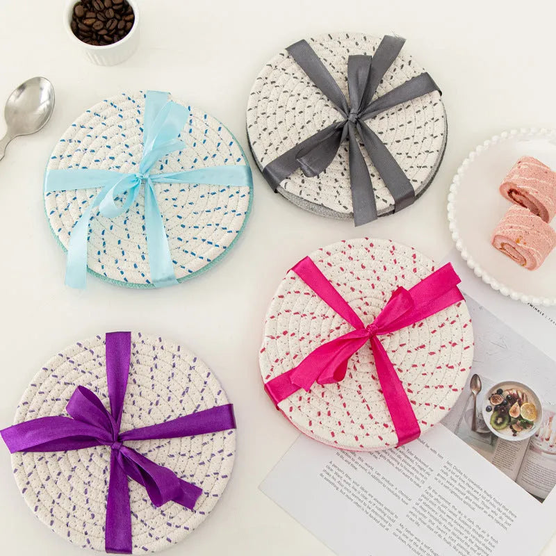 Three round cotton cord coasters in coordinating colours on wooden table
