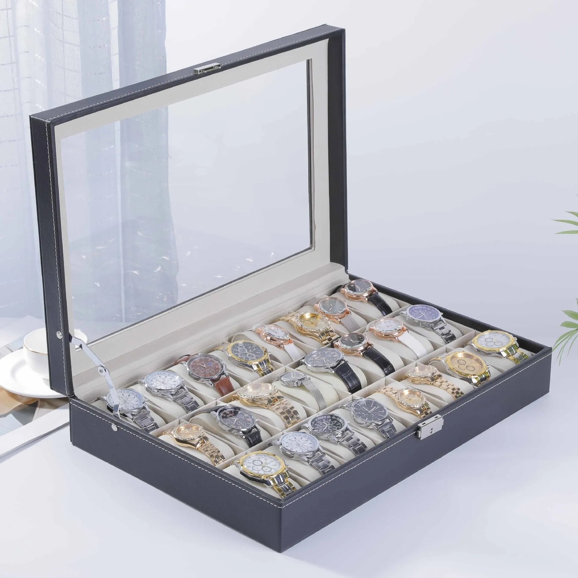 Grey leather watch storage box with transparent lid showing multiple watch slots inside.