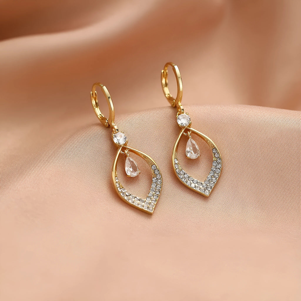 Close-up of a woman's gold-coloured water drop tassel earring with a teardrop shape and dangling details.