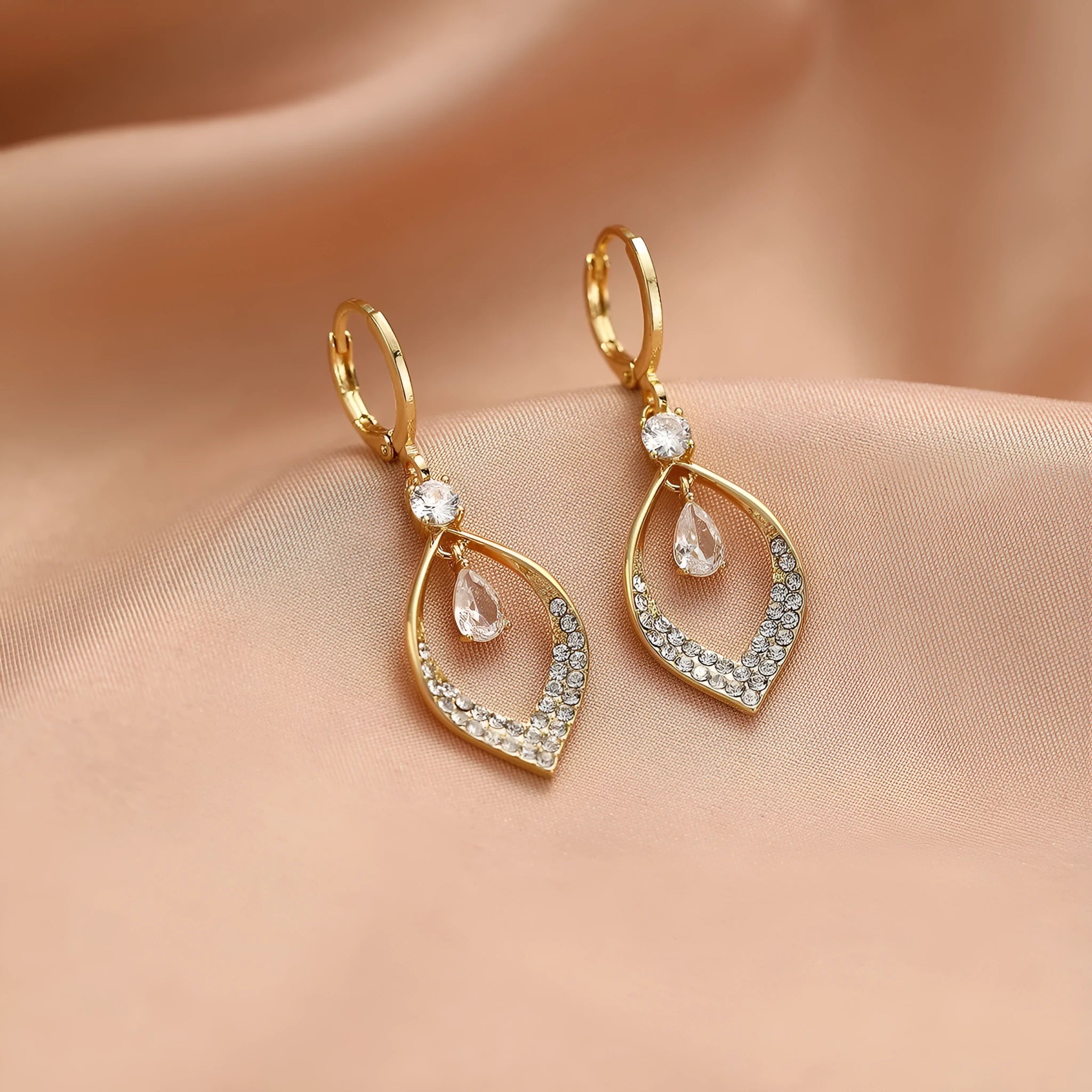 Close-up of a woman's gold-coloured water drop tassel earring with a teardrop shape and dangling details.