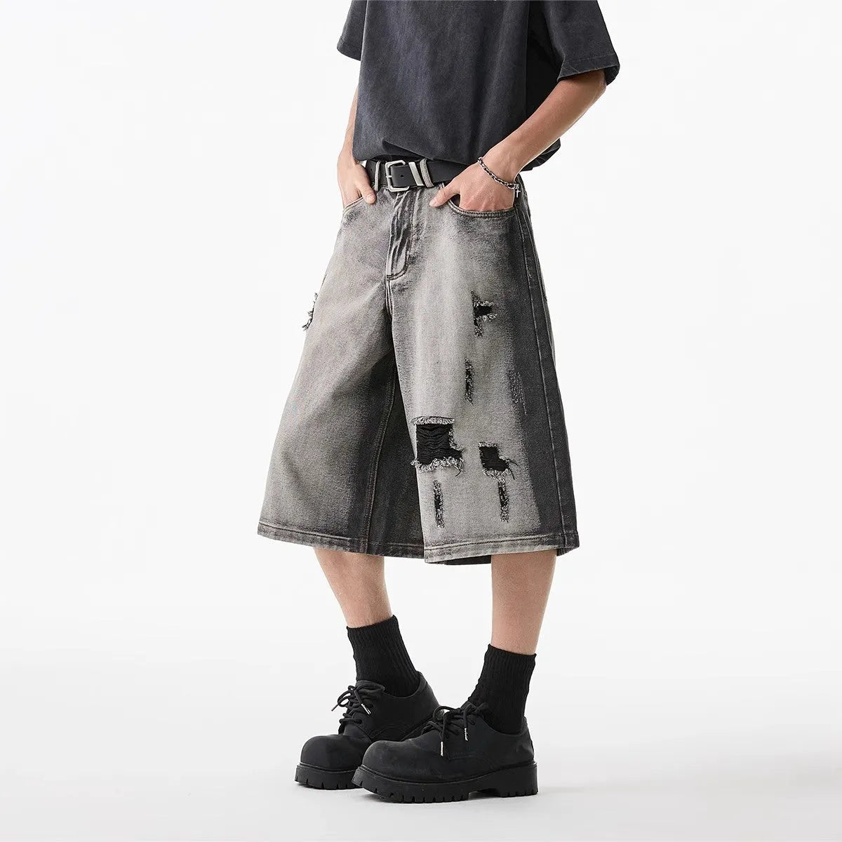 Grey loose fit denim shorts with distressed holes and a cropped length on a hanger.