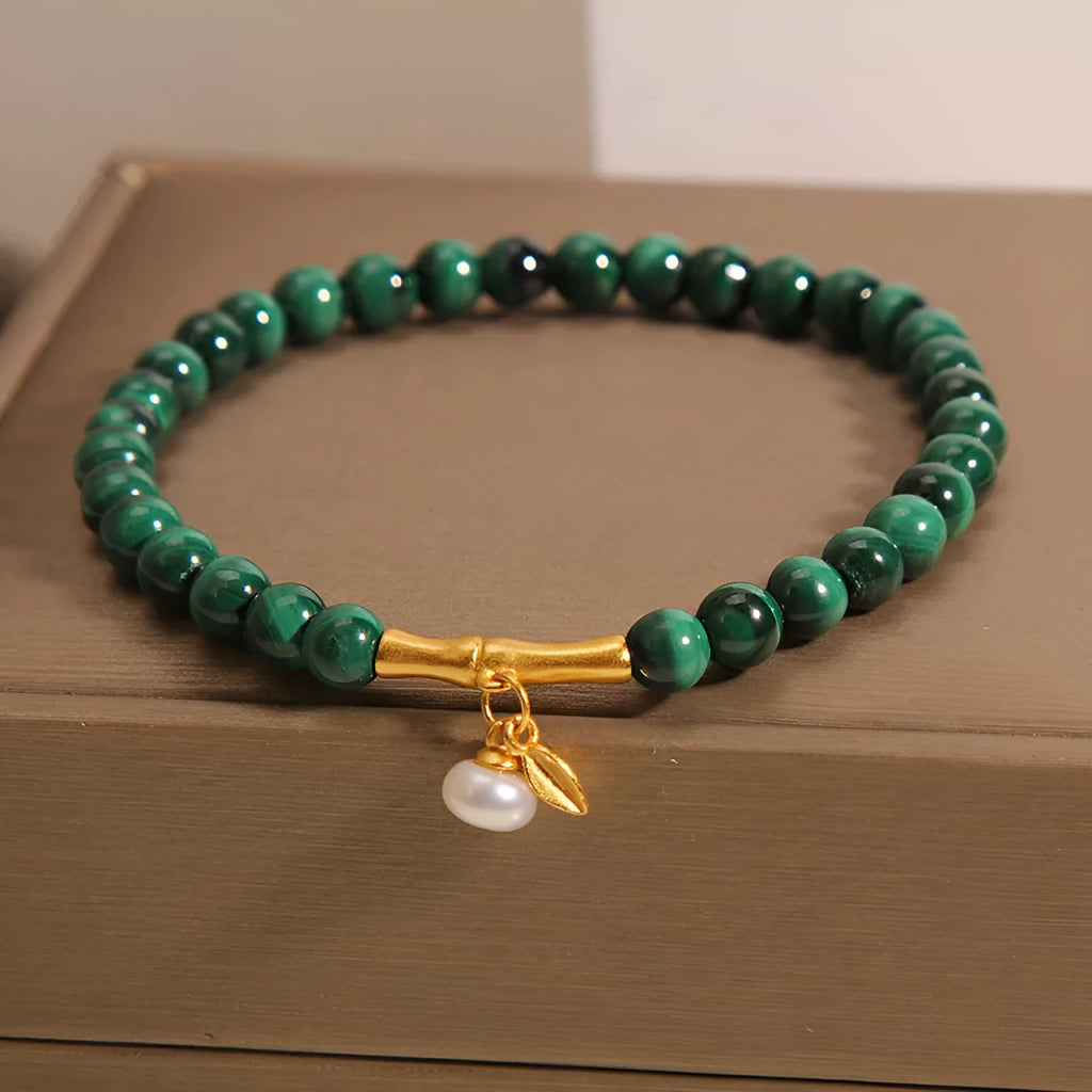 Close-up of a women's white crystal bracelet with a lucky bamboo charm on an elasticated band.